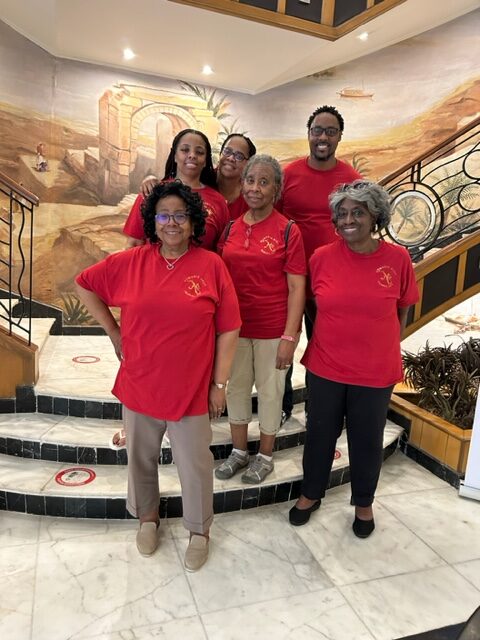 A group of women in red shirts standing on a staircase.