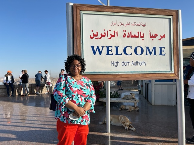 A woman standing in front of a welcome sign in arabic.