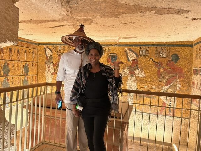 A man and woman standing in front of an ancient egyptian tomb.