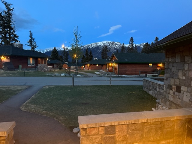 A view of the lodge at dusk with mountains in the background.