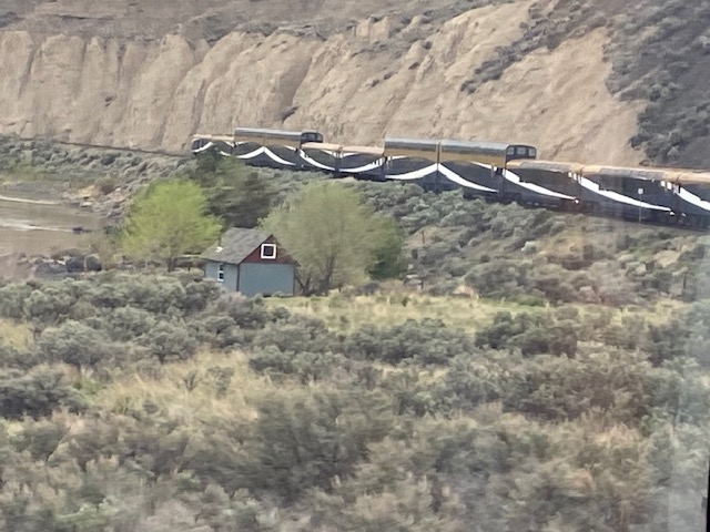 A train traveling down a hill with a house in the background.