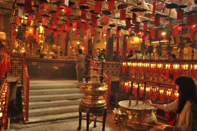 A woman is praying inside a chinese temple.