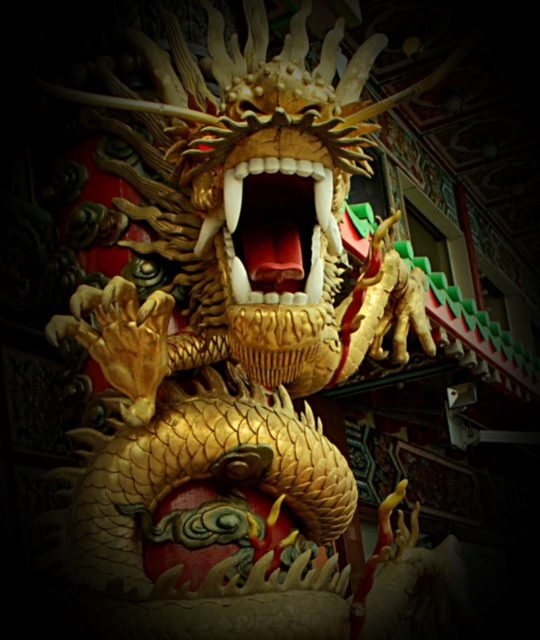 A golden dragon statue in front of a dark building.